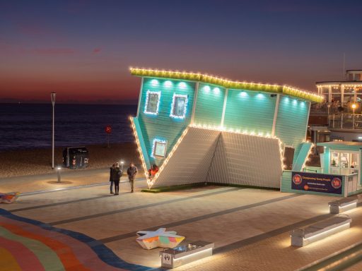 Custom Colorful building with lights at sunset, located near the beach. Couples walking nearby.